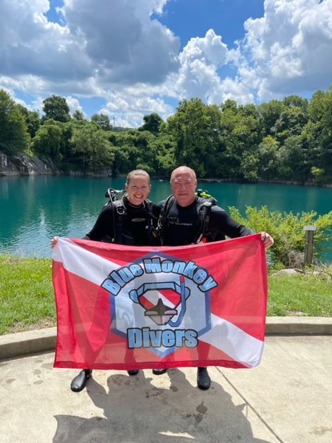 A newly certified diver with Coach McCain and the Blue Monkey Divers flag